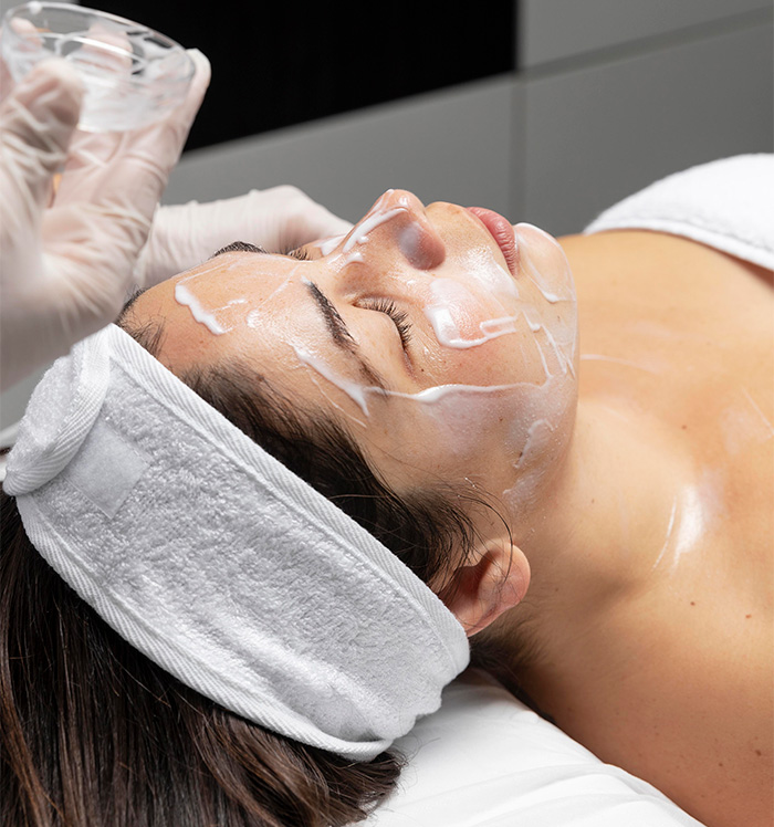 Primer plano de manos profesionales realizando un masaje relajante con aceites en las piernas de una clienta.